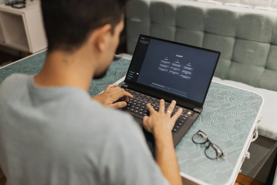 A professional working remotely on a laptop, surrounded by abstract AI interface elements, signifying future collaboration.