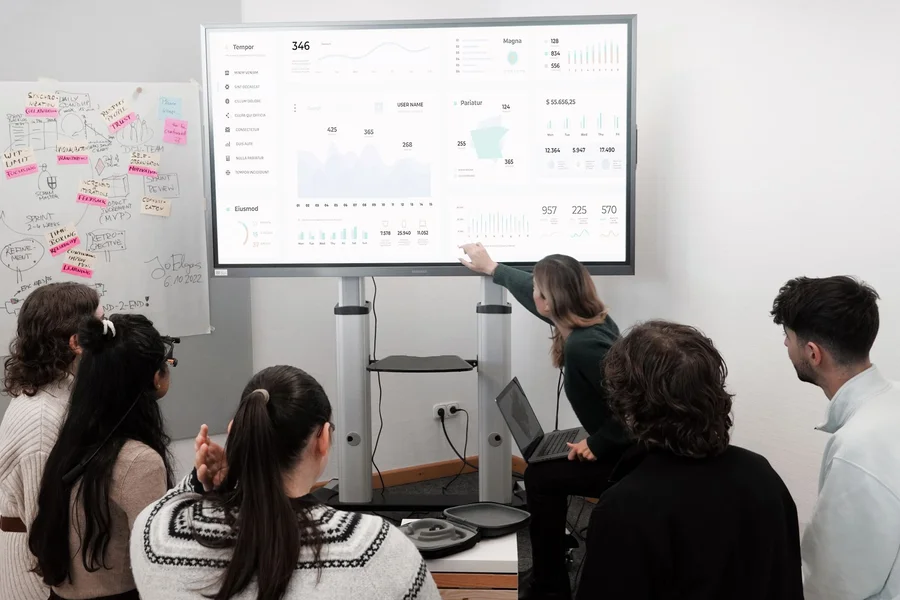 Small Business CRM Analytics A team reviewing customer analytics data displayed on a large office screen