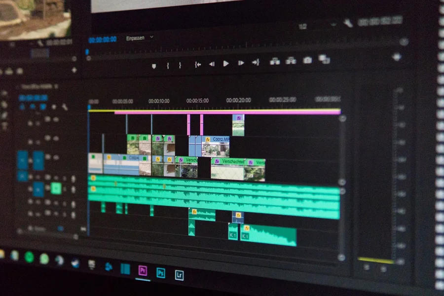 A computer monitor displaying video editing timeline tracks and audio waveforms