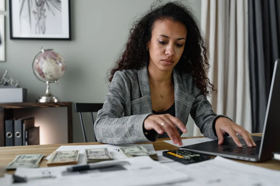 A person managing personal finances on a smartphone and laptop at a desk
