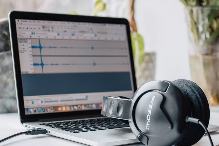 Audio waveform sound editing software displayed on a studio monitor with headphones
