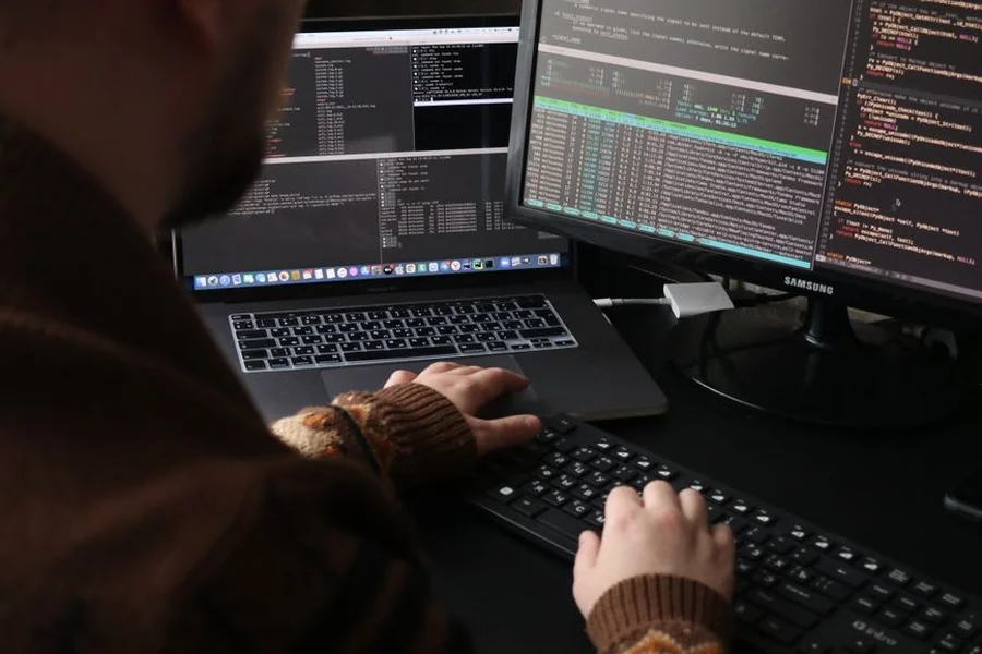 Developer Writing AI Agent Code A software developer writing Python agent code on dual monitors in an office setting