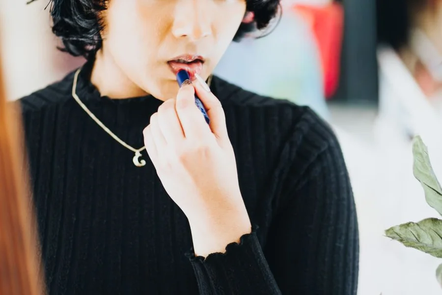 Applying bold Cosmic Moon metallic lipstick with mirror for festival makeup